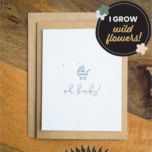 "oh baby" written in calligraphy on a plantable seed paper greeting card with an illustration of a blue baby stroller