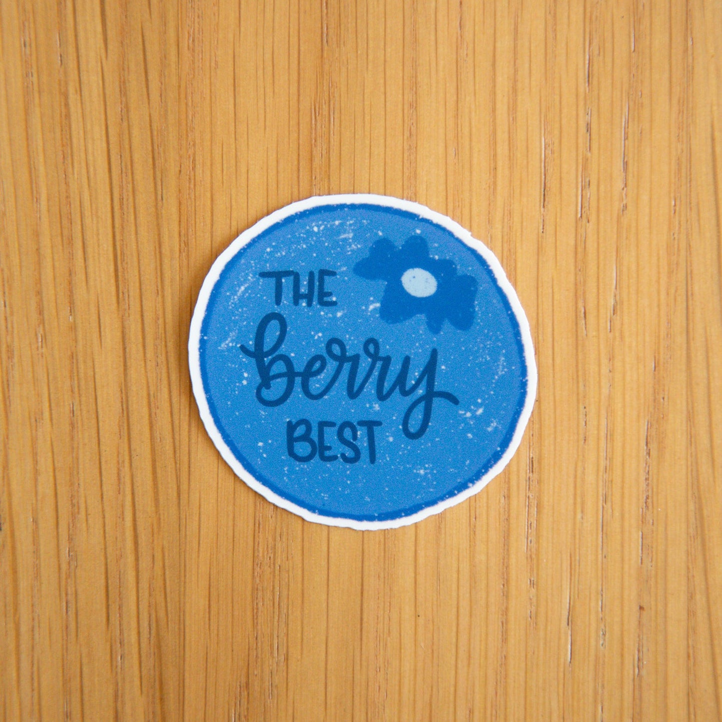 Blueberry round sticker with 'The Berry Best' text on a wooden surface
