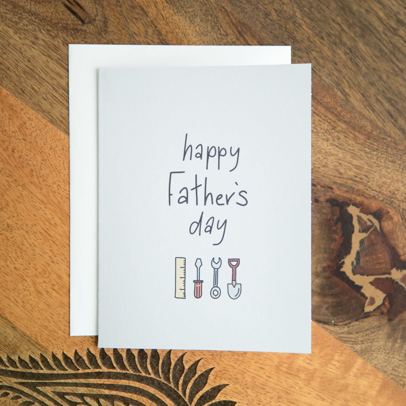 Greeting card with 'Happy Father's Day' text and tools on a wooden surface