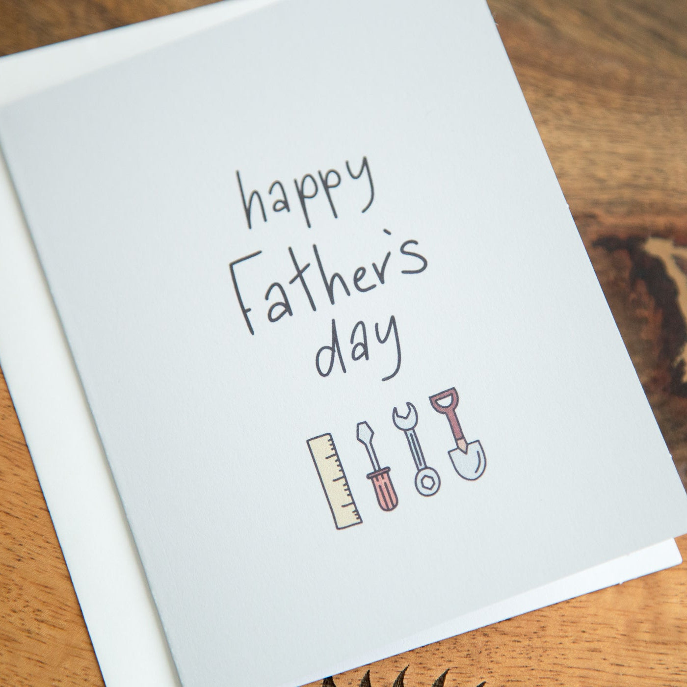 Greeting card with 'Happy Father's Day' text and tool illustrations on a wooden surface