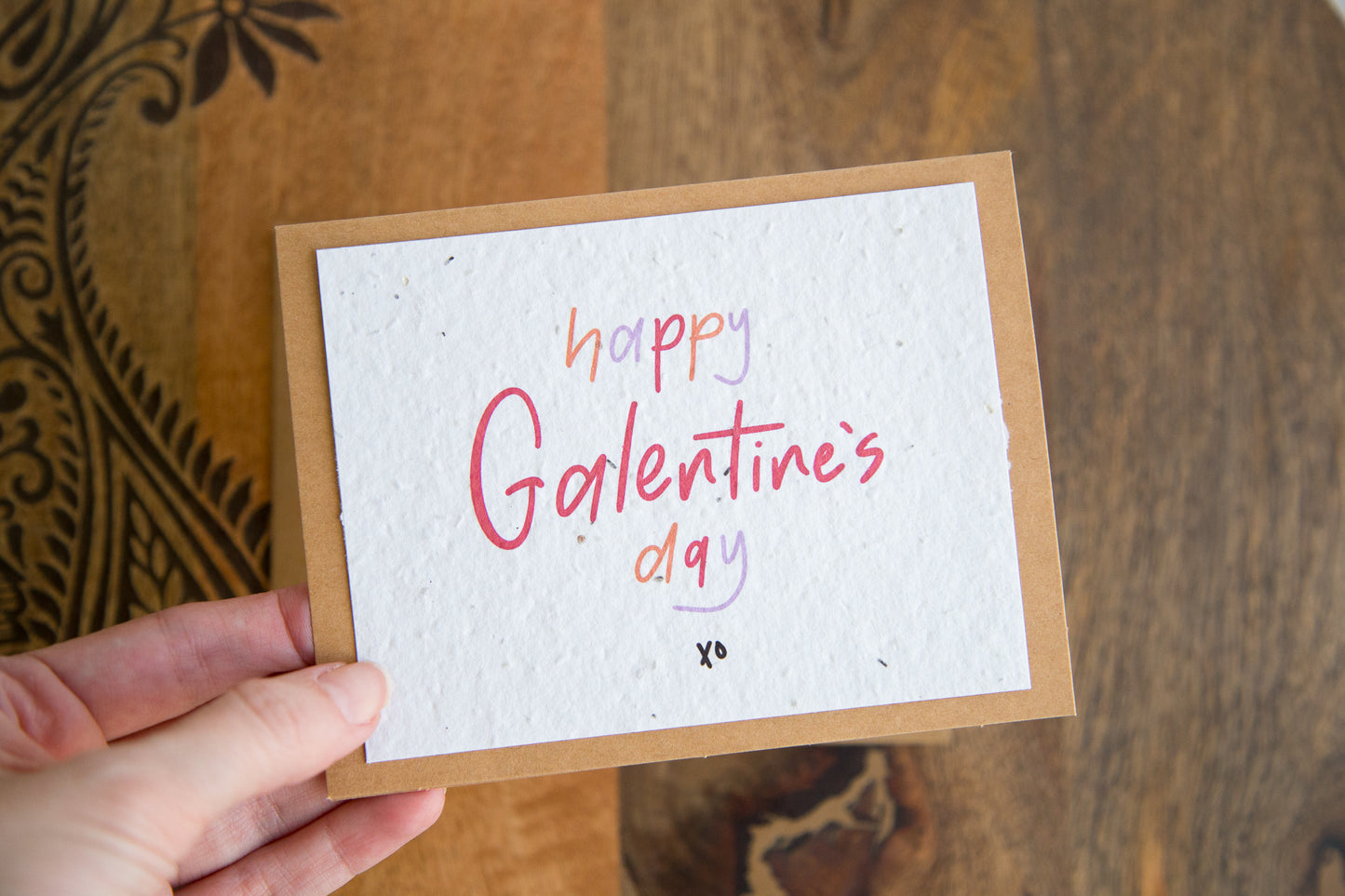 White greeting card with the words “happy Galentine’s Day xo” written in red orange and purple on plantable seed paper