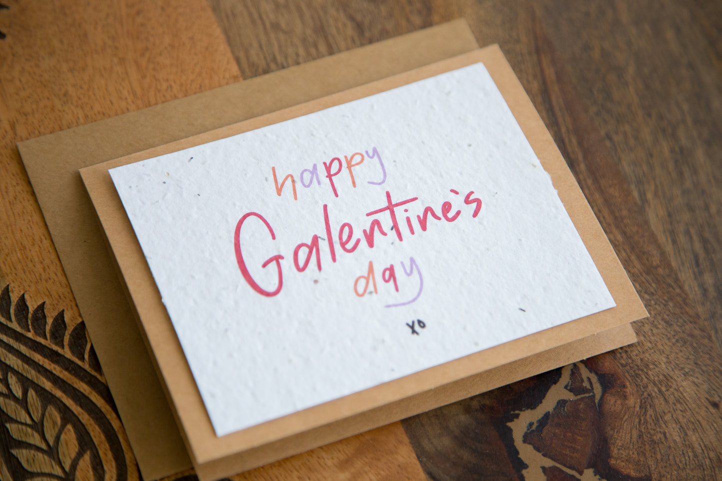 White greeting card with the words “happy Galentine’s Day xo” written in red orange and purple on plantable seed paper