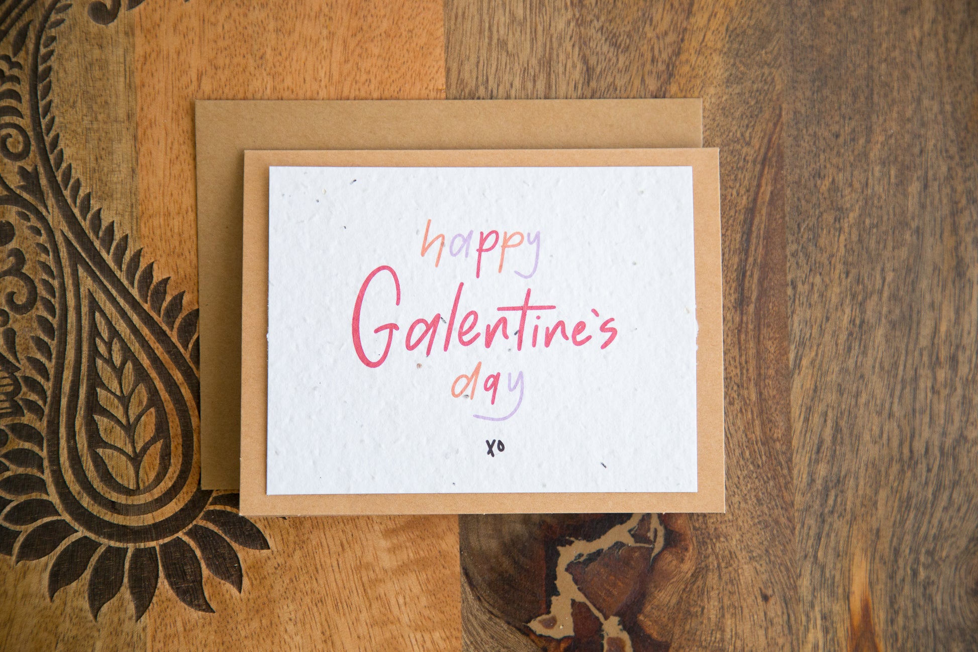 White greeting card with the words “happy Galentine’s Day xo” written in red orange and purple on plantable seed paper