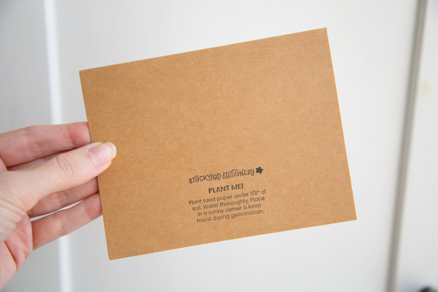 The back of a kraft paper greeting card with a stamp saying "Plant me! Plant seed paper under 1/8" of soil. Water thoroughly. Place in a sunny corner & keep moist during germination"