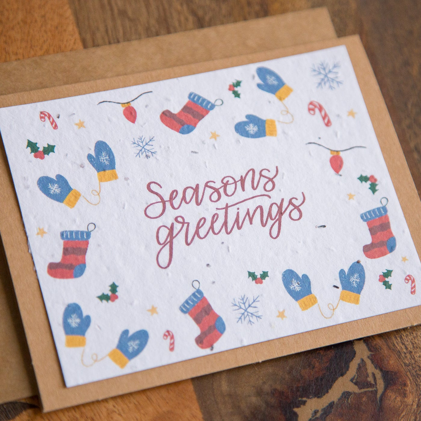Seasons greetings card with winter-themed illustrations on a wooden surface