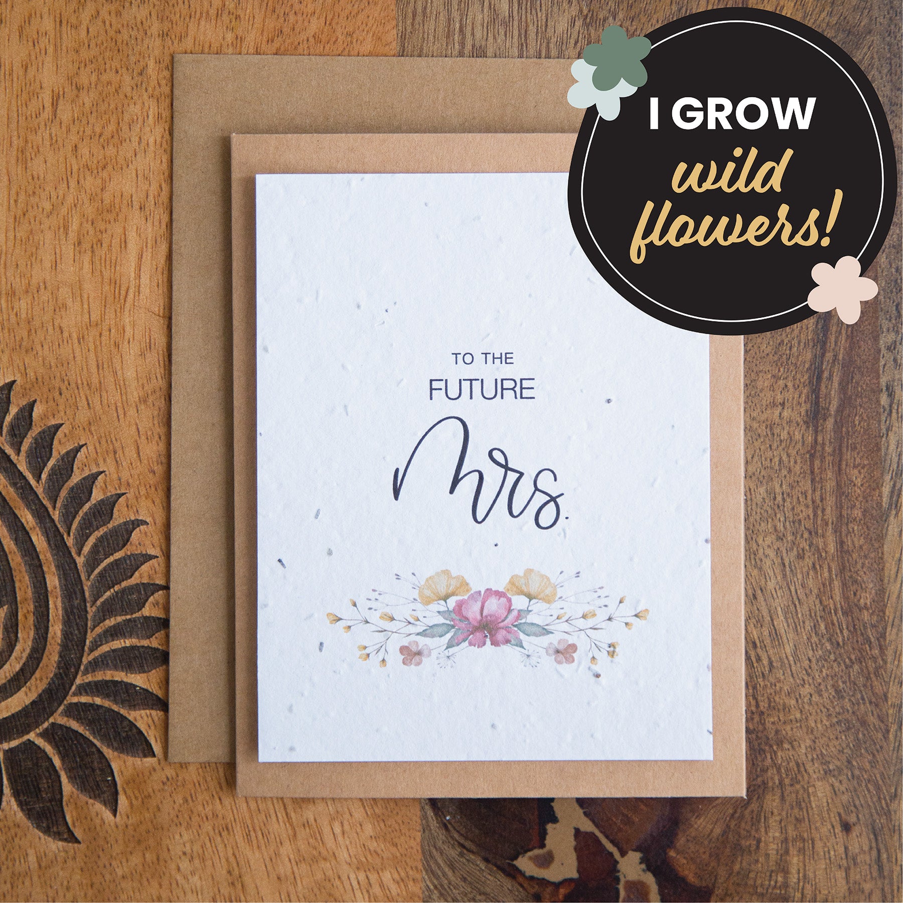 A kraft greeting card with the works “to the future Mrs.” Printed on plantable seed paper. A flower wreath sits below the text.