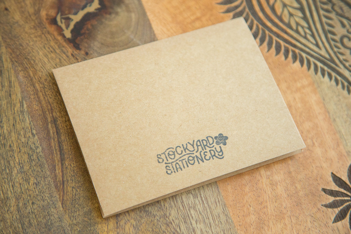 Back of an A2 sized greeting card with a black logo stamped in ink