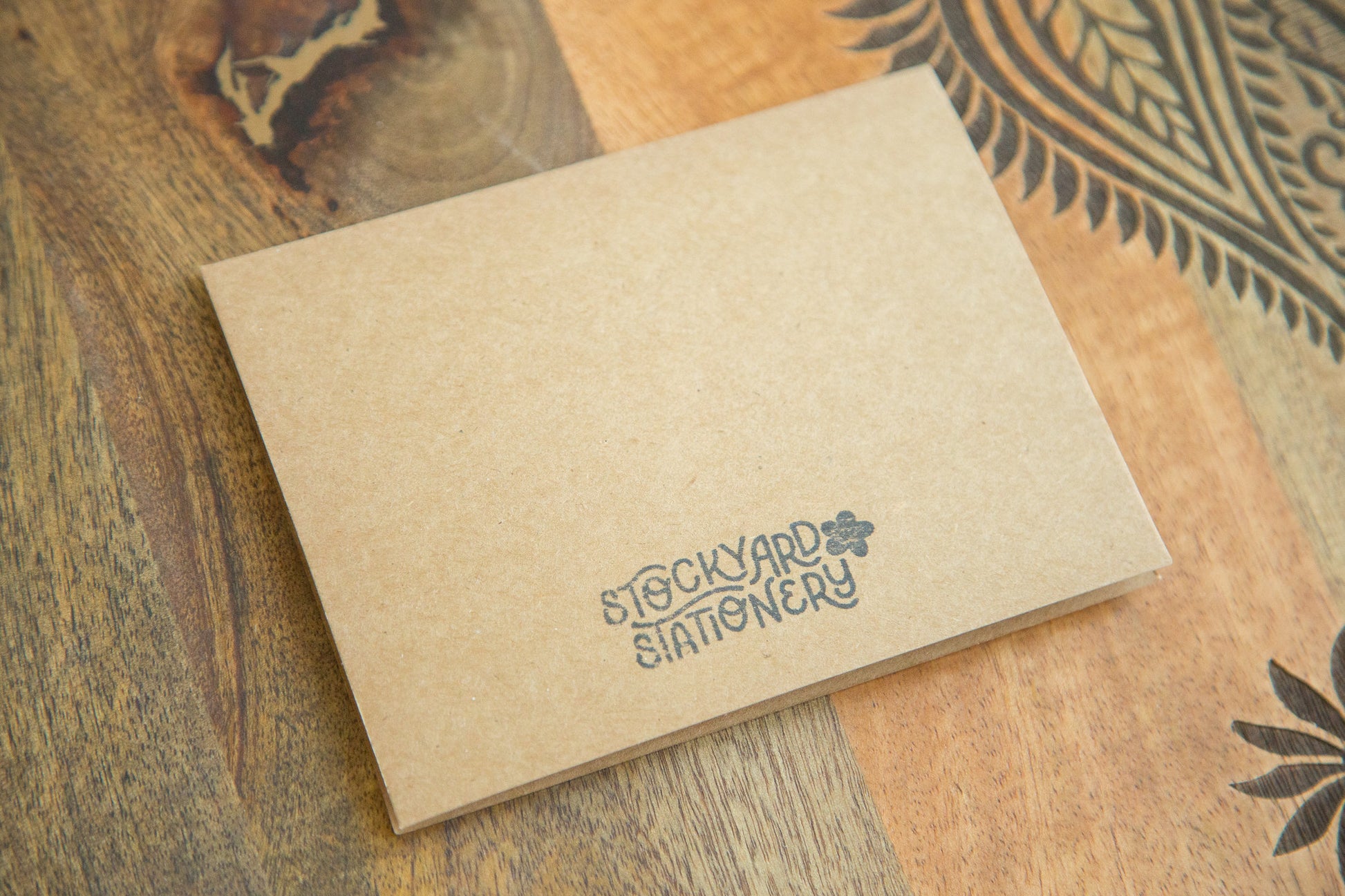 Back of an A2 sized greeting card with a black logo stamped in ink