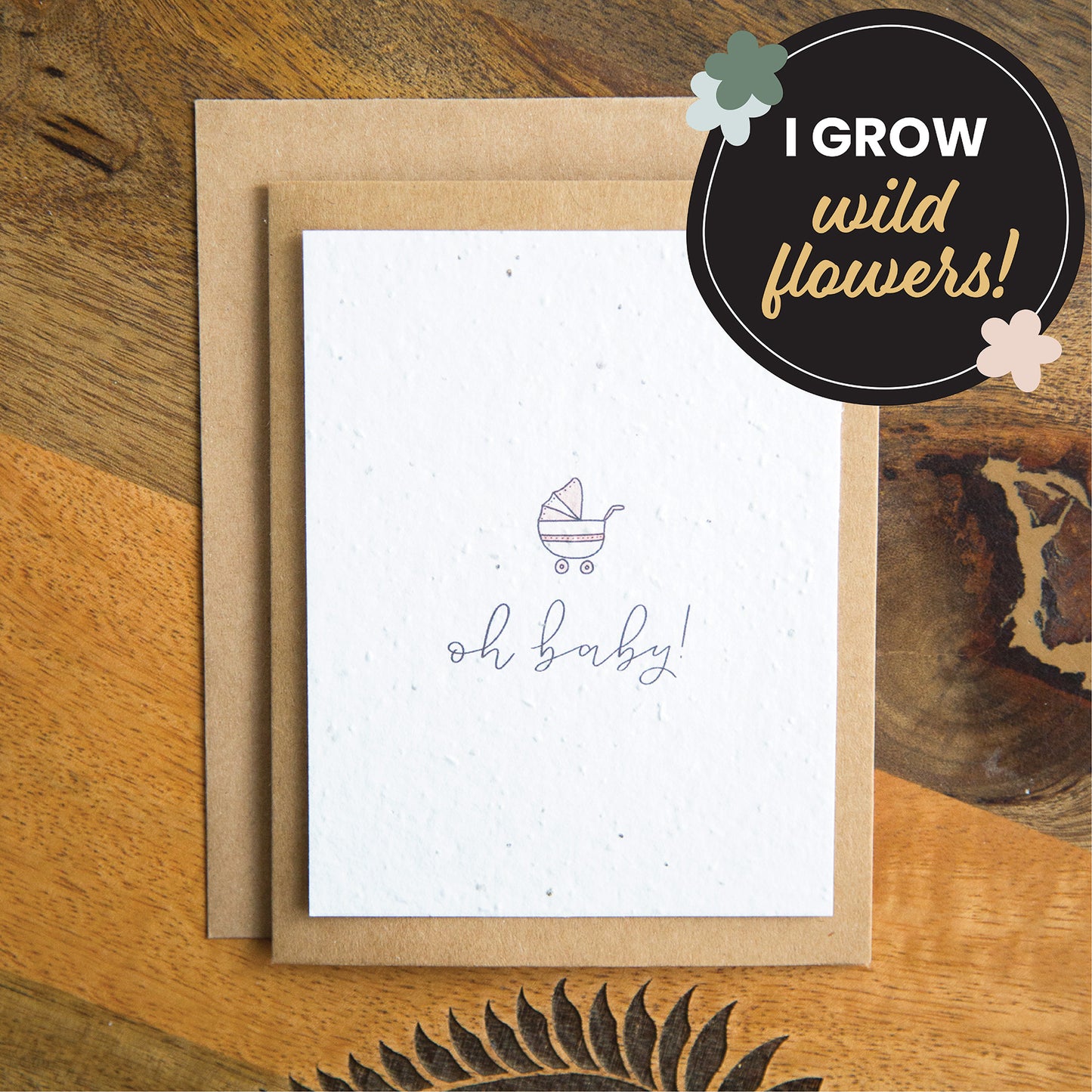 "oh baby" written in calligraphy on a plantable seed paper greeting card with an illustration of a pink baby stroller