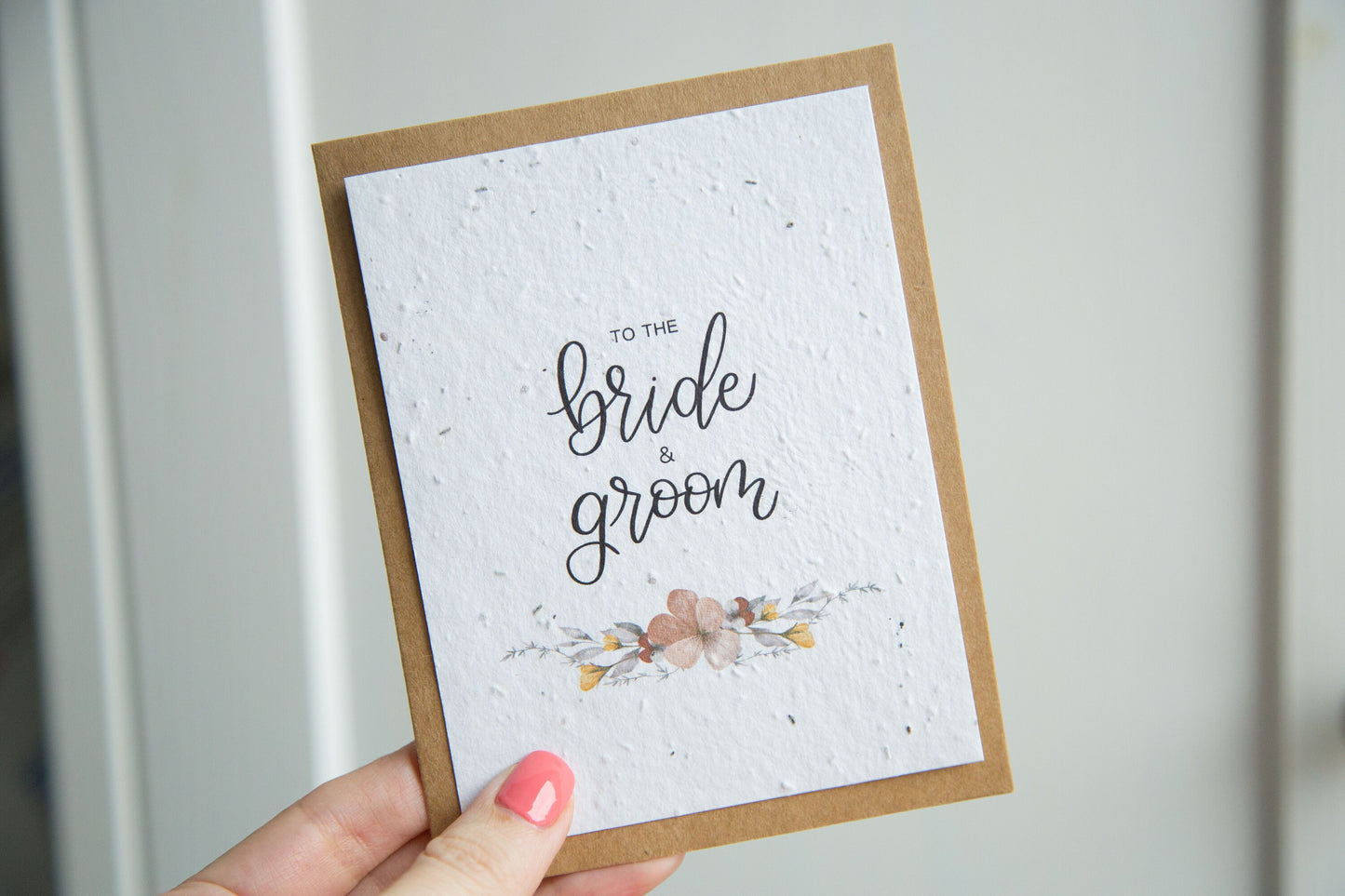 An A2 sized wedding card with floral designs and the text 'To the bride & groom' on the front, on white plantable seed paper