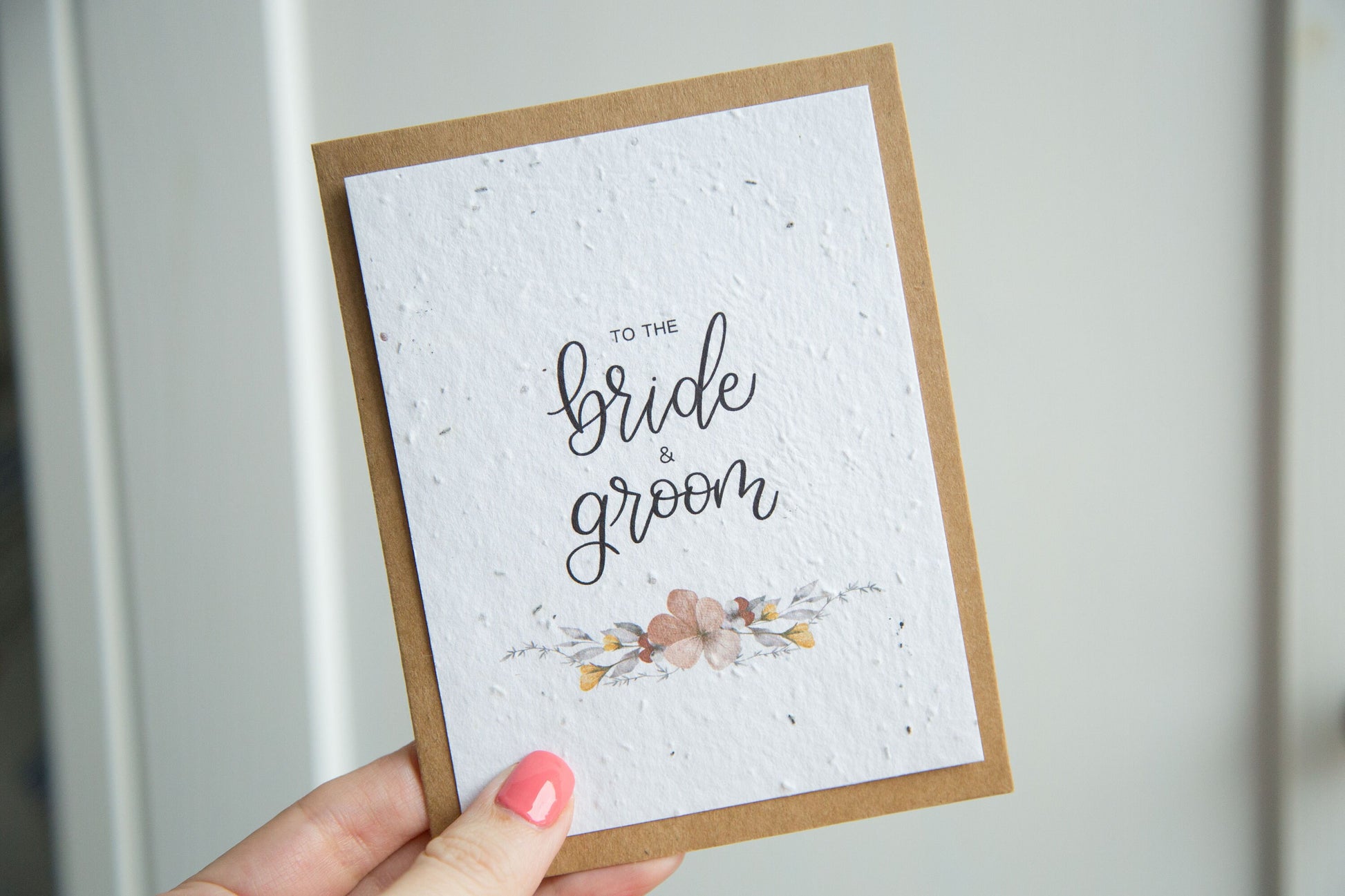 An A2 sized wedding card with floral designs and the text 'To the bride & groom' on the front, on white plantable seed paper